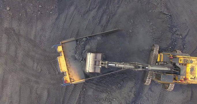 Top view excavator loads coal into a dump truck