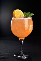 fruit drink in glass cup with orange piece on black background