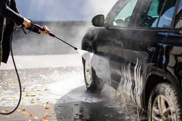 Young man washing car cleaning with foam and hi pressured water