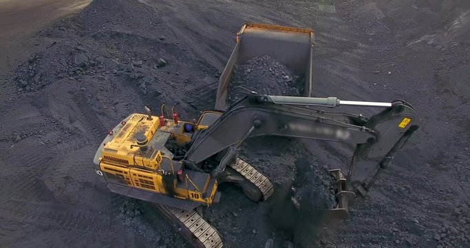 Aerial view from drone excavator loads coal into a dump truck