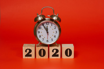 new year 2020 concept, alarm clock with the year 2020 written on wooden blocks