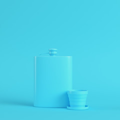 Hip flask with cup on bright blue background in pastel colors. Minimalism concept