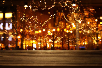 Fototapeta na wymiar background Image of wooden table in front of street view in front of abstract blurred lights