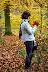 Woman is using her smartphone in the autumn forest