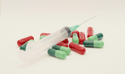 Green capsules red capsules and a syringe isolated