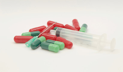 Green capsules red capsules and a syringe isolated