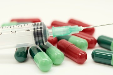 Green capsules red capsules and a syringe isolated