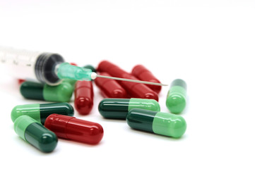 Green capsules red capsules and a syringe isolated