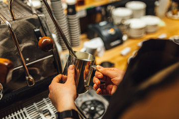 Close up view Barista steaming milk in metal pitcher. Barista making coffee.