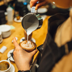 Barista pouring latte art in coffee cup, barista making coffee.