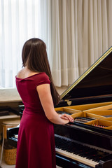 Elegant young pianist is standing in front of a piano in a hall
