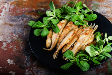 Fried smelt on a black plate