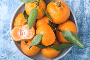 Tangerines with leaves in a dish on a blue background