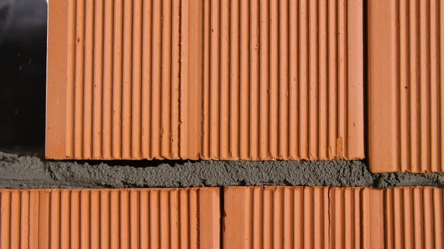 Close-up of brick block put on cement. Stock footage. Masonry blocks of ceramic red brick for foundation of house. Man lays brick on cement for bonding with rest of masonry
