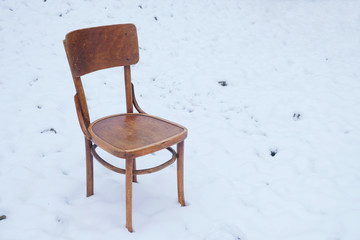 Vintage wooden chair on snow surface in Ukraine. The concept of solitude. Self-isolation concept. Unexpected concept. Copy space.