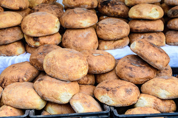 Heap of freshly baked whole-grain bread displayed for sale at a street food market, healthy food photographed with soft focus