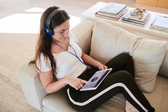Woman with tablet controlling home cheating on sofa.