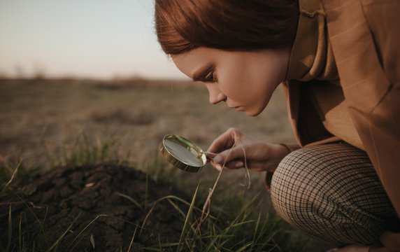Young woman examining dirt pile