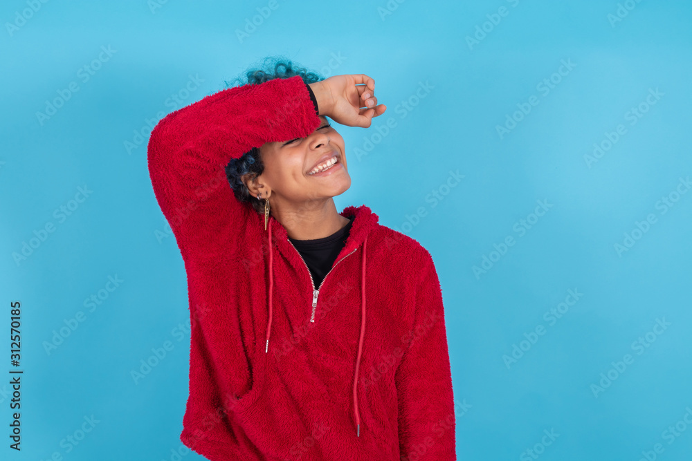 Wall mural young woman or afro american girl isolated on blue background with expression