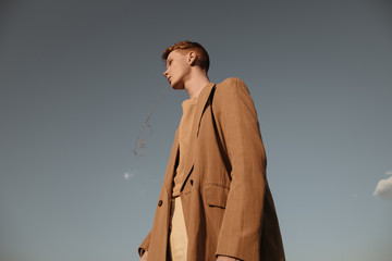 Stylish guy with straw in field