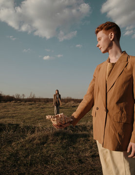 Young man holding woman in seashell in field