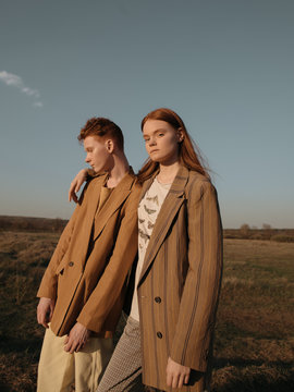 Red head brother and sister standing in field