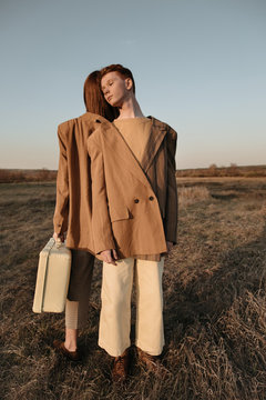 Siblings with suitcase in field