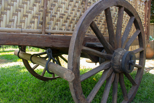 Rear part of an old ox cart, picturing the wooden wheel and the break system