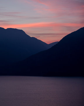 A sunset over layered mountains on the coast