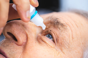 Elderly person puts eye drops in the eye