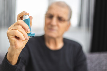 Elderly person using an asthma spray - obrazy, fototapety, plakaty
