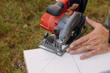 Fototapeta premium Carpenters hands cutting wood with electric saw