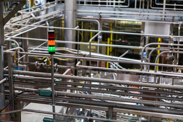 three colors signal lamp, red, orange, green, next to hot water metallic pipes selective focus, packaging area, and belt conveyor systems background