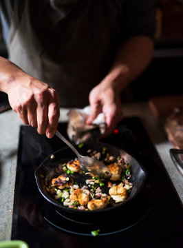 Man cooking delicious food in frying pan on electric stove