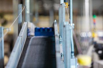 A belt conveyor system selective focus and close up view, aluminum beer cans on the factory packaging industrial machine, modern brewhouse brewery