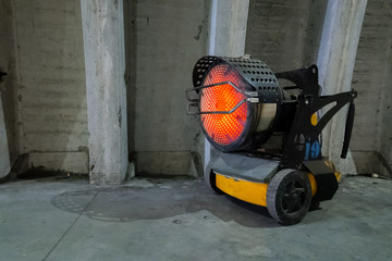 Heavy duty industrial heater blowing hot air in cold building interior. Heat compressor or heat fan propeller, propelling warm air in cold constructions