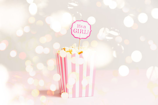 It's A Girl Sign In A Popcorn Bag At The Baby Shower Party. Empty Minimalistic Party Background. Baby Shower Celebration Concept. Horizontal With Festive Holiday Bokeh
