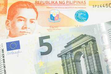 An orange twenty peso note from the Philippines close up in macro with a five Euro note from the European Union eurozone