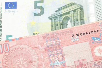 A red ten taka note from Bangladesh, close up in macro with a five Euro note