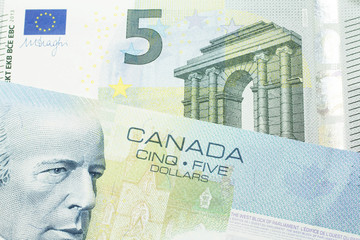 A close up macro shot of a blue five Canadian dollar bill with a five Euro note
