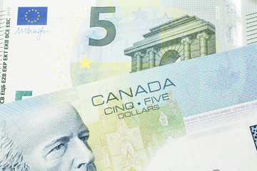A close up macro shot of a blue five Canadian dollar bill with a five Euro note