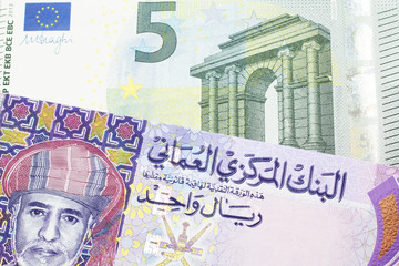 A multicolored one rial note from Oman, close up in macro with a blue and green five Euro bill