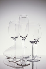 Glassware selection with wine, champagne, liquour glasses and decanter on the light background.. Fine cristal glassware concept. Vertical in light cold toning