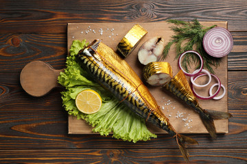 Tasty smoked fish on wooden table, top view