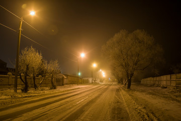Winter in the village. Night shot of a road with lanterns