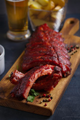 Rack of ribs, barbecue sauce, fries and light beer. Vertical image
