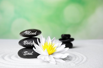 Stones with words Mind, Body, Soul and lotus flower on white sand. Zen garden