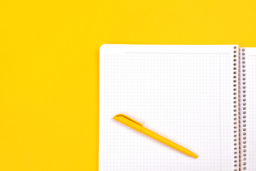 Top view of yellow pen with clean white notebook open with copy space on solid yellow table background for presentation, writer or school education, blogger, novel and friction or brand story concept.