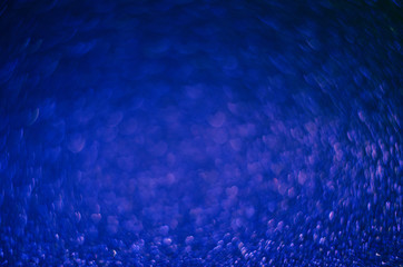 Classic Blue color. Color of the year 2020. Abstract festive bokeh background with shining defocus sparkles. Blurred glitters shimmering dust macro close up, copy space for text logo