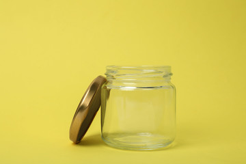 Open empty glass jar on light yellow background